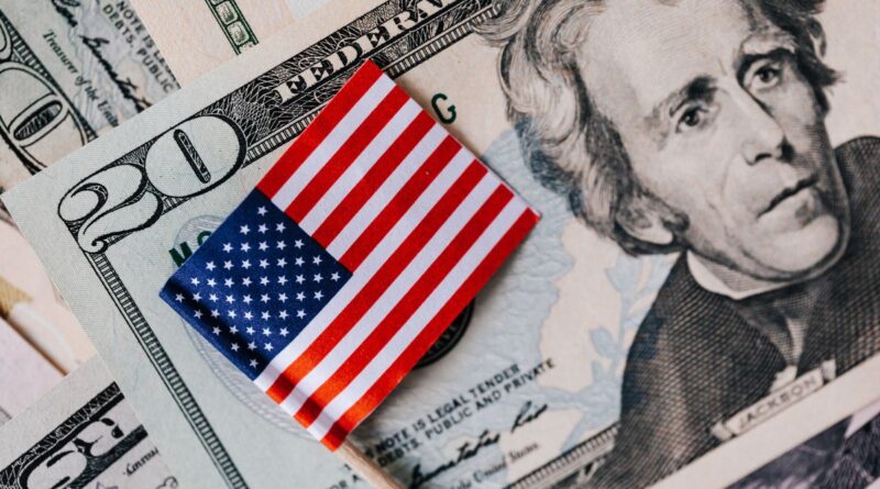 Close-up of U.S. dollar bills with a small American flag on top