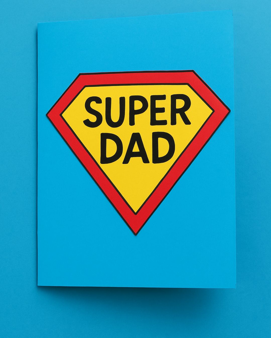 Handmade Super Dad Father’s Day card with red and yellow emblem on blue background