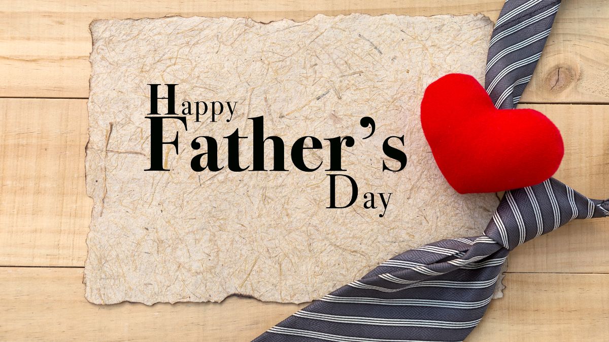 Happy Father’s Day card with red heart and striped tie on wooden background