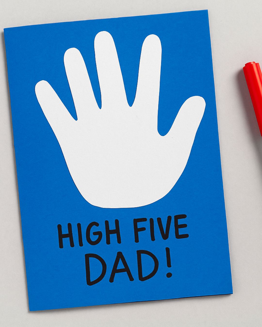Handmade Father’s Day card with white handprint and “HIGH FIVE DAD!” text on blue paper