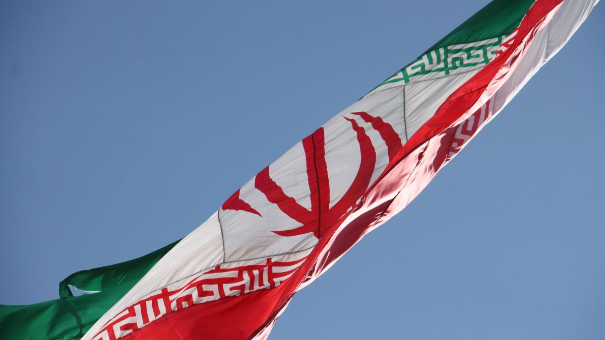 Iranian national flag waving against a clear blue sky
