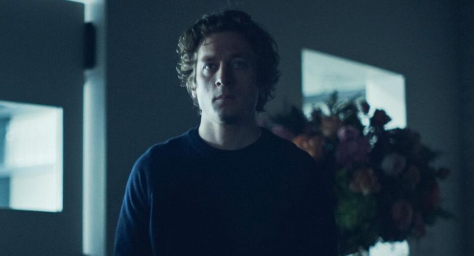 Jeremy Allen White in a moody scene from The Bear Season 4, standing in low light with a serious expression