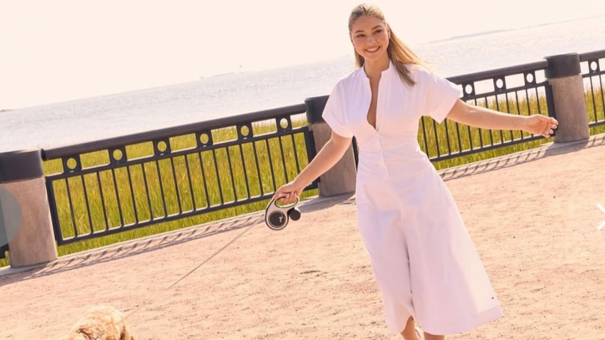 Madelyn Cline walking her dog by the waterfront in a white dress