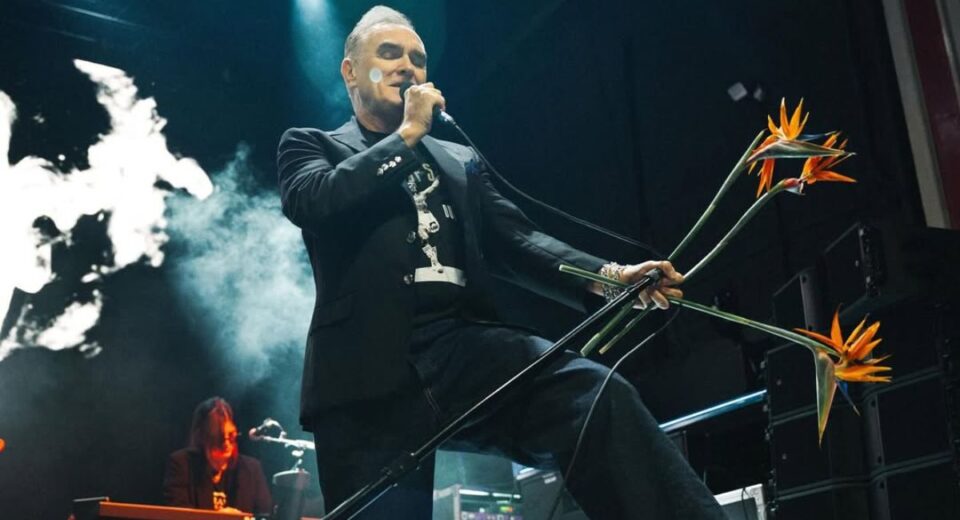 Morrissey performing live with microphone and flowers