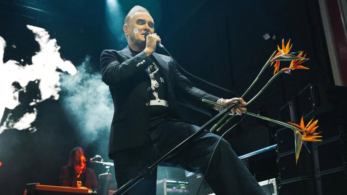 Morrissey performing live with microphone and flowers