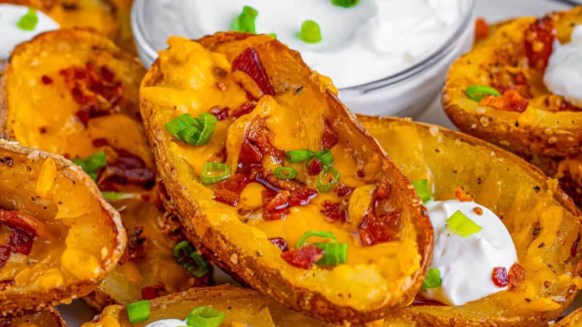 Loaded potato skins topped with cheddar, bacon, green onions, and sour cream