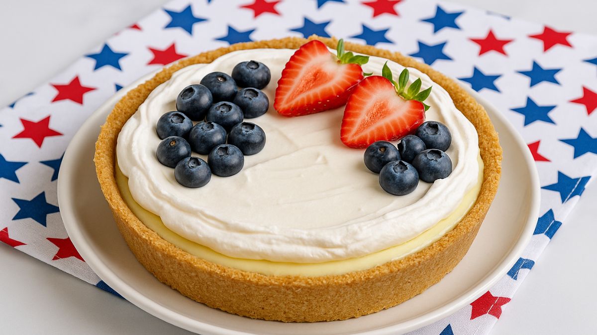 No-bake lemon icebox pie with graham cracker crust, whipped cream topping, blueberries, and strawberries on a patriotic star-patterned napkin.