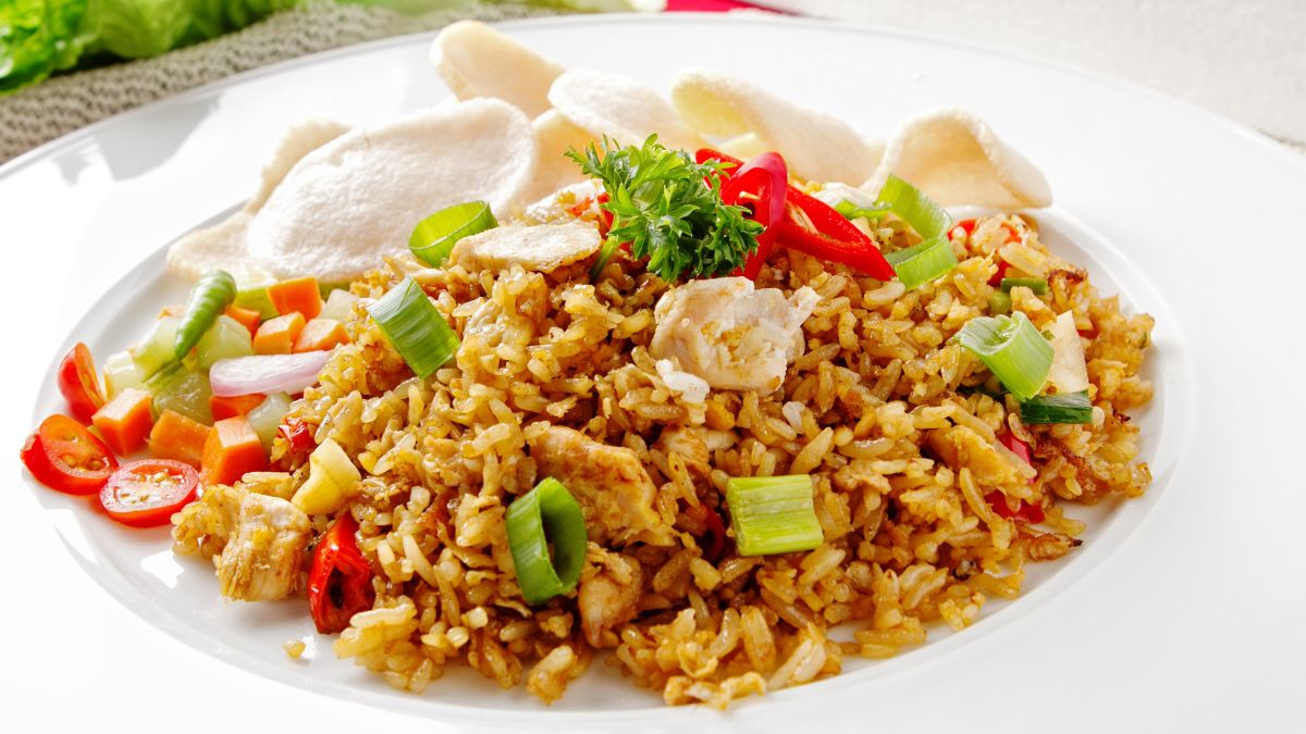 Plate of egg fried rice with vegetables, garnished with green onions and served with crackers