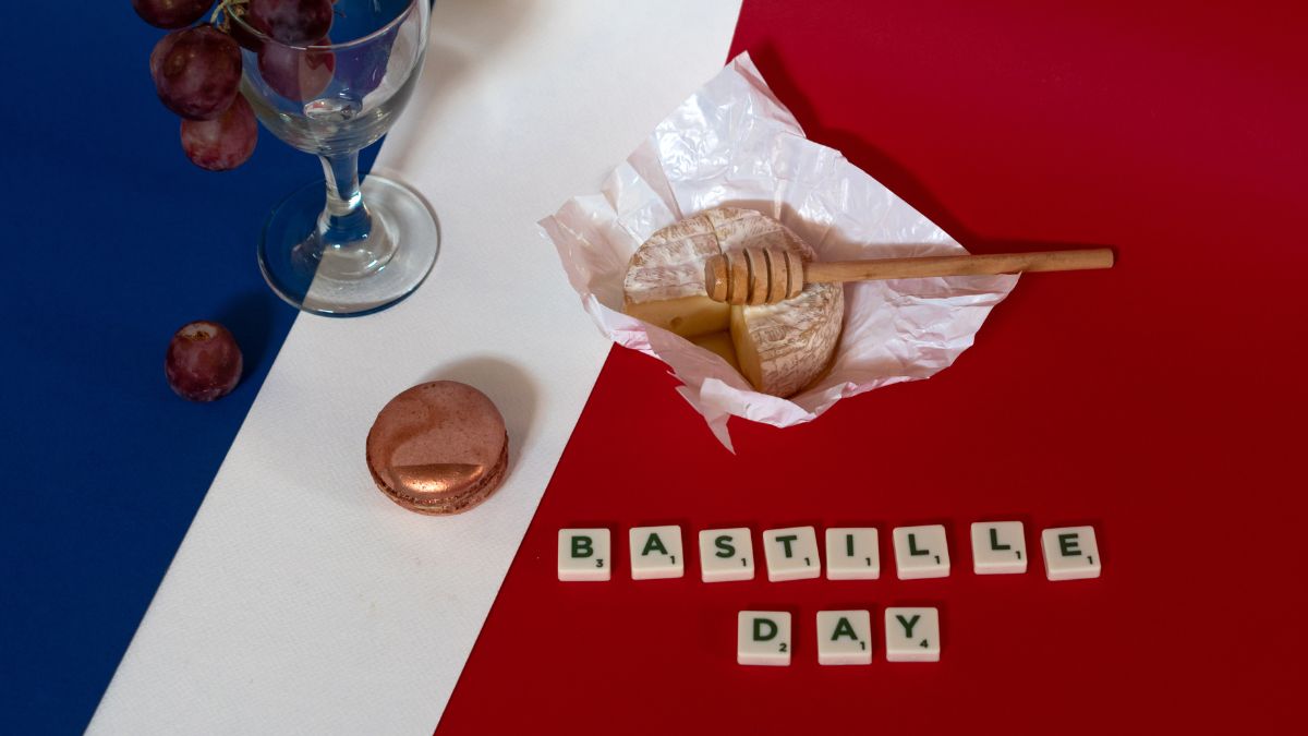 French cheese, grapes, macaron, and honey on tricolor background with Bastille Day text