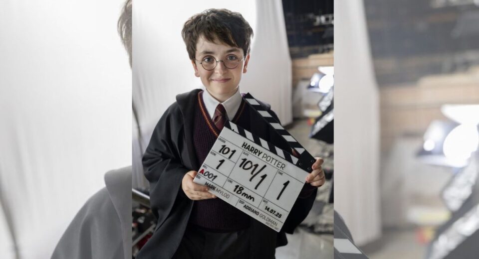Dominic McLaughlin dressed as Harry Potter holds a clapperboard on the HBO series set