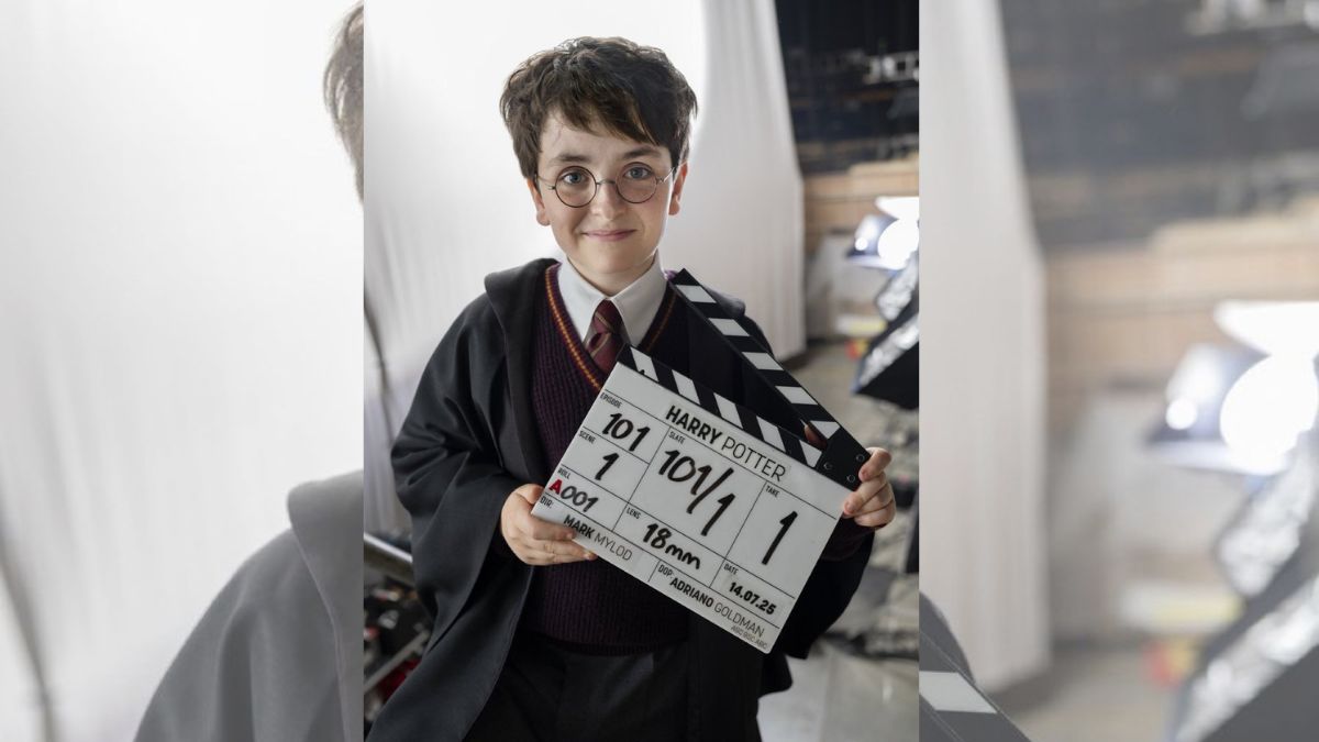 Dominic McLaughlin dressed as Harry Potter holds a clapperboard on the HBO series set