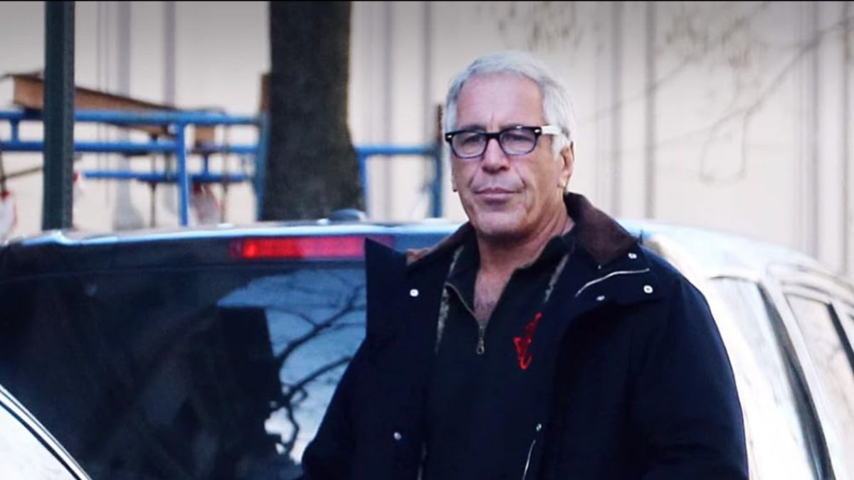 Jeffrey Epstein walking outside near a parked car
