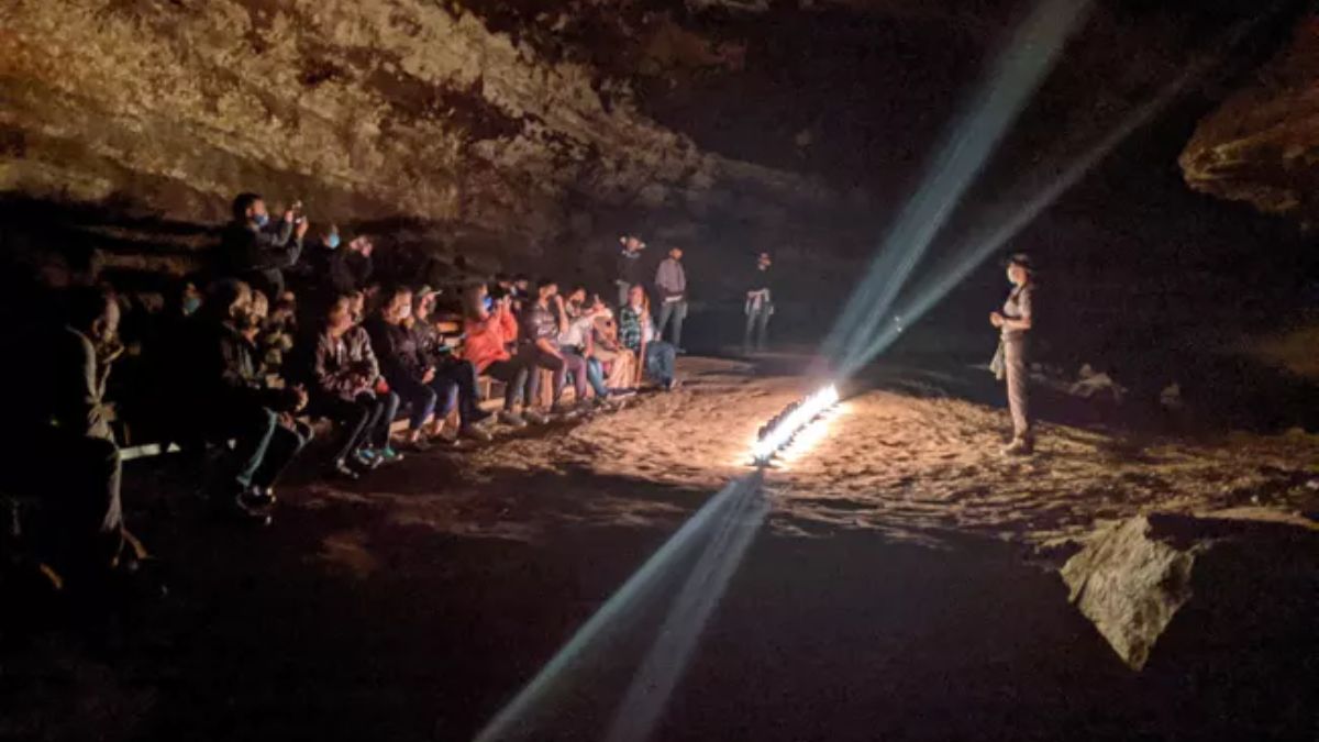 Lantern-lit tour group listening to a ranger inside Mammoth Cave’s Star Chamber