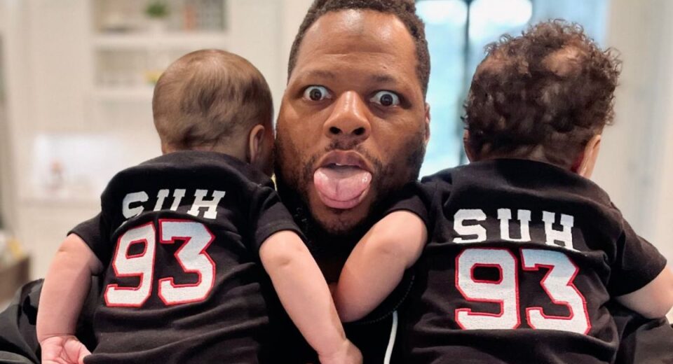 Ndamukong Suh holding his twin babies wearing matching Suh #93 jerseys