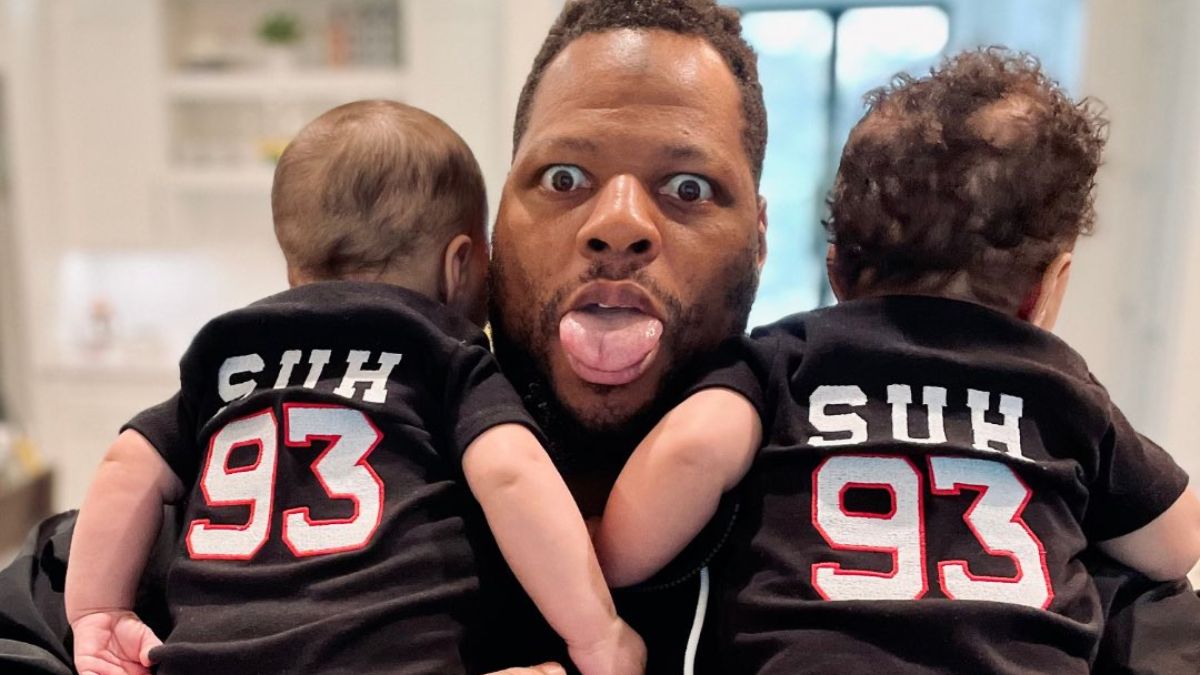 Ndamukong Suh holding his twin babies wearing matching Suh #93 jerseys