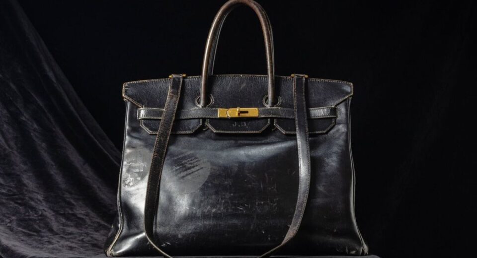 Jane Birkin’s original black Hermès Birkin bag displayed on dark velvet backdrop